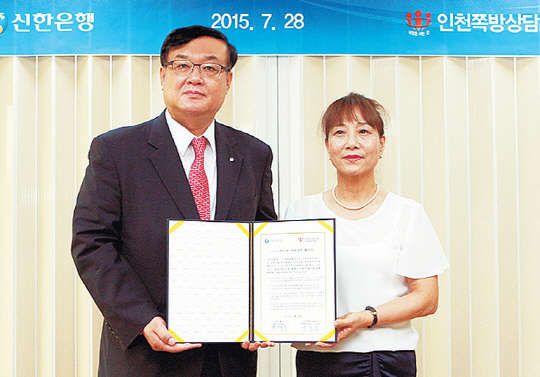 왕태욱 신한은행 부행장(왼쪽)과 박종숙 인천쪽방상담소 소장이 28일 자매결연식 후 기념촬영을 하고 있다.   신한은행 제공